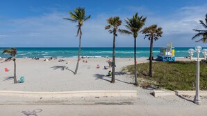 A beach with palm trees, a lifeguard tower, and a clear blue sky. - Paradise Oceanfront HBH (Hollywood)