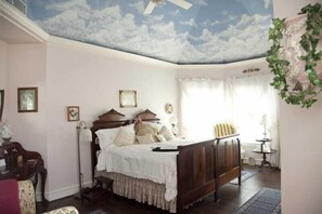 A bedroom with a bed, a ceiling fan, a window with curtains, and a wall-mounted plant. - Lillian Farms Bed & Breakfast (Washington)