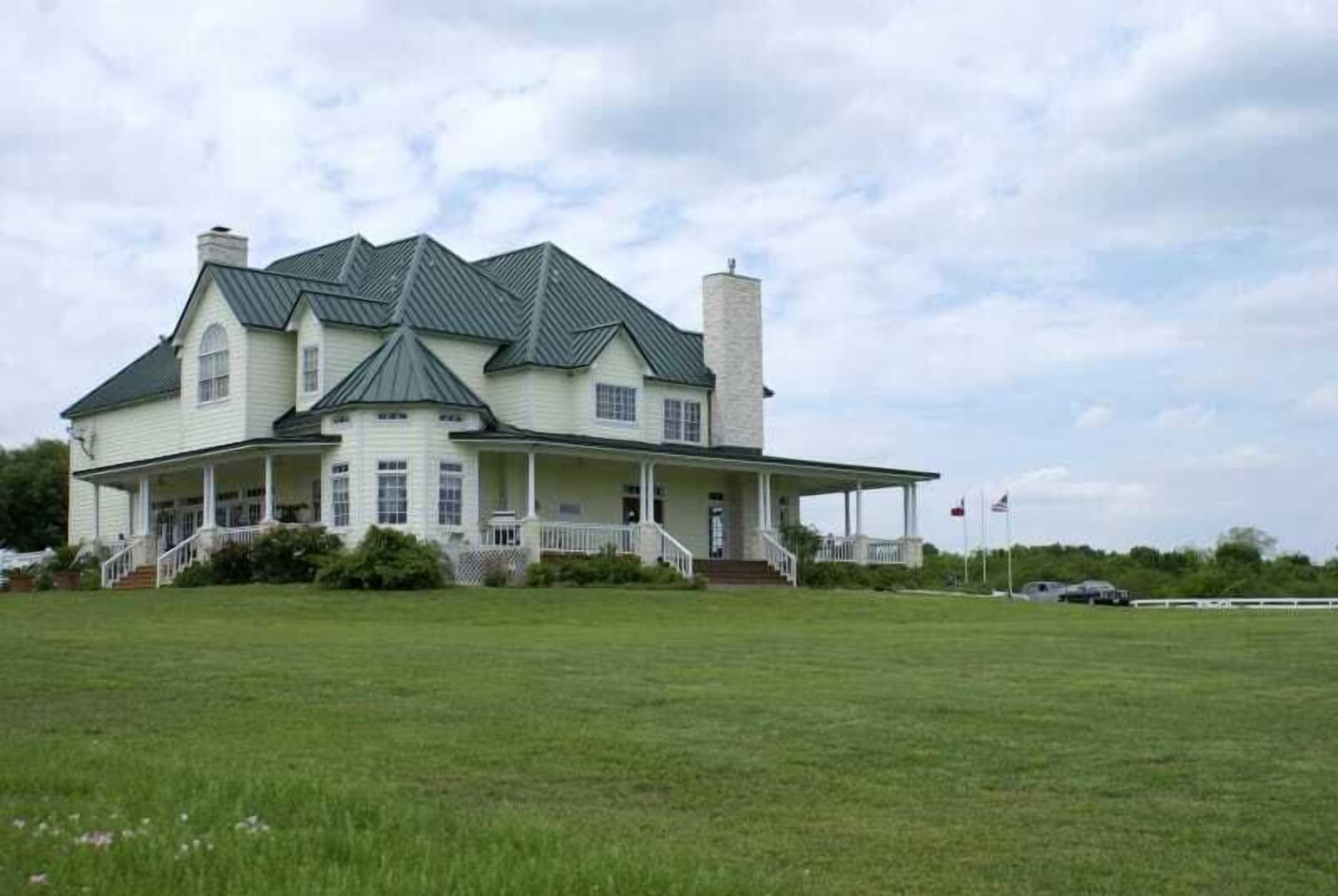 A large, single-story house with a wrap-around porch and a chimney.