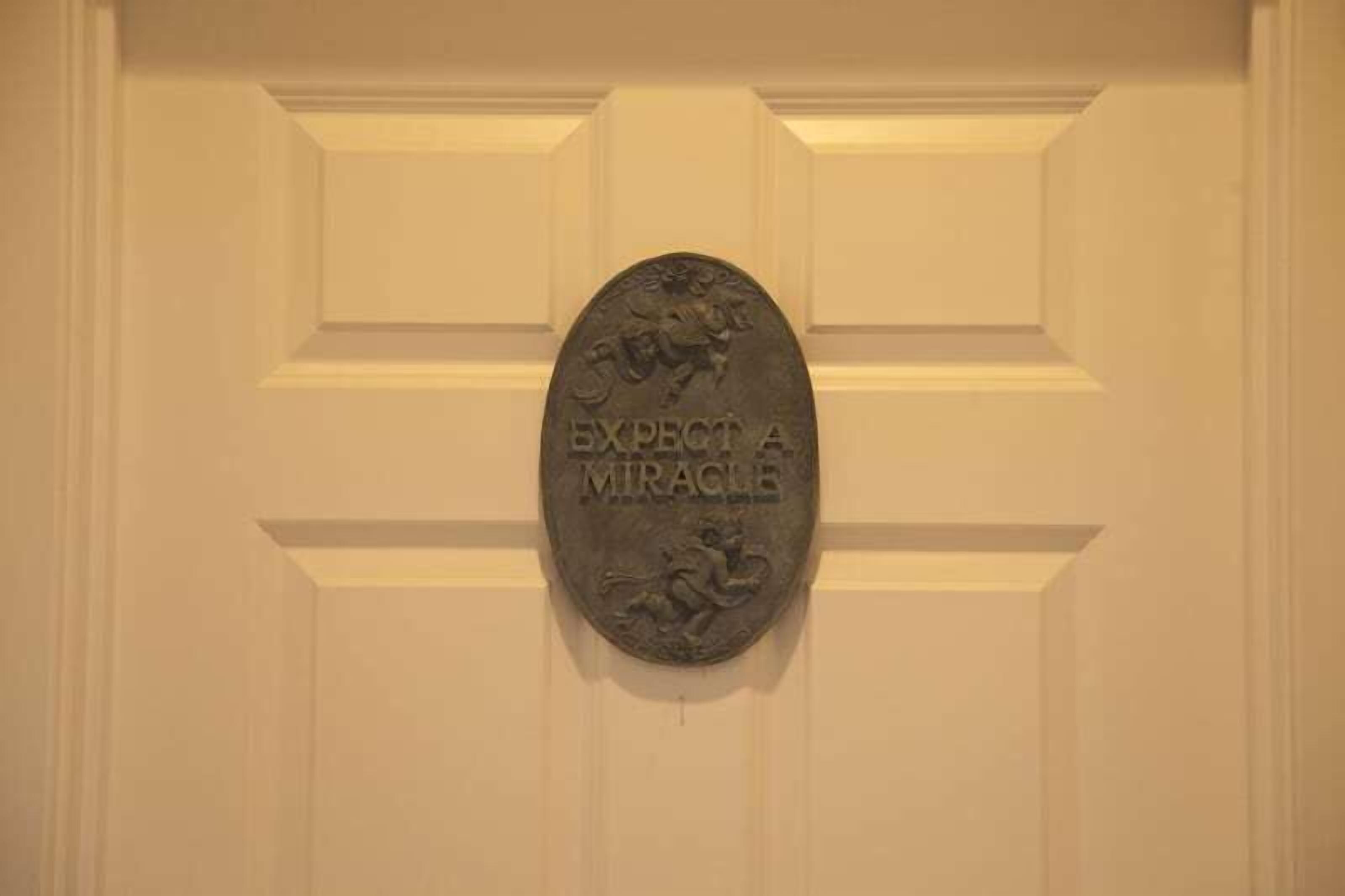 Una puerta con una placa de latón que dice "ESPERA UN MILAGRO".