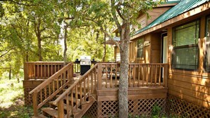 A wooden cabin with a wooden deck, a grill, and a covered porch. - Lillian Farms Bed & Breakfast (Washington)