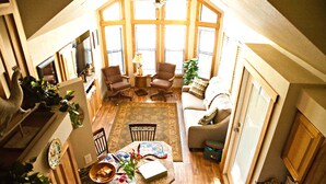 A spacious living room with a high ceiling, large windows, and a cozy seating area. - Lillian Farms Bed & Breakfast (Washington)