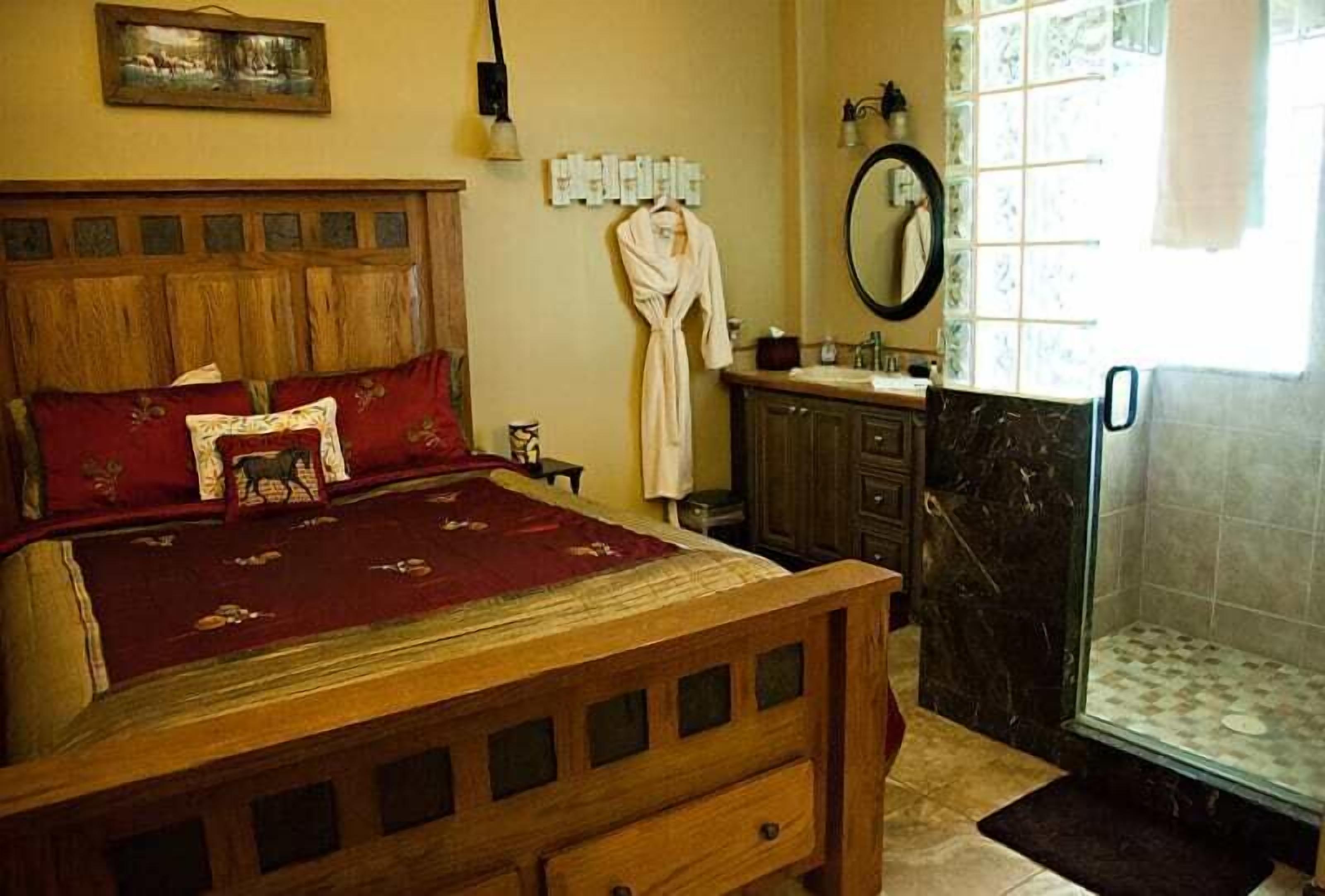 A bedroom with a wooden bed, a bathroom with a mirror, and a shower.