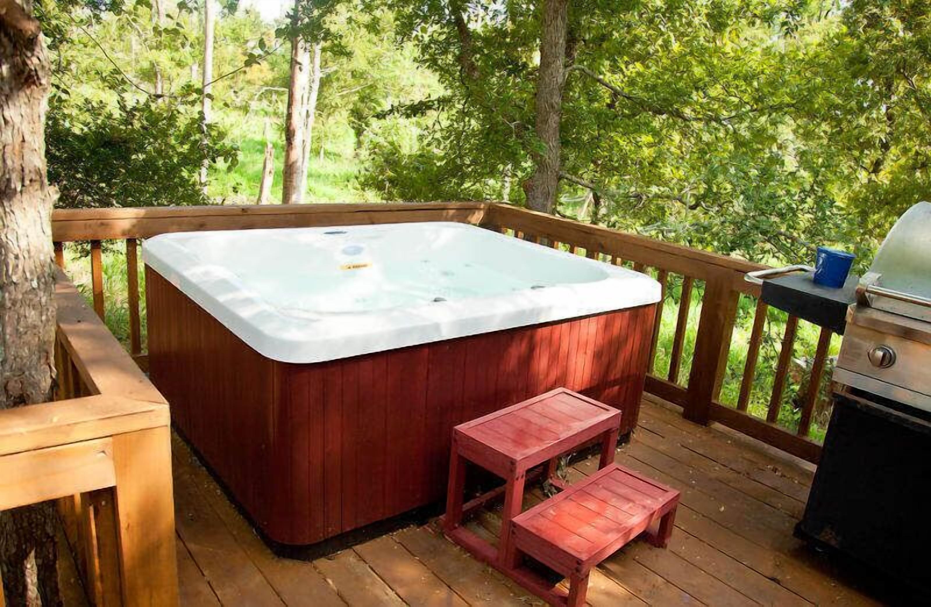 A hot tub on a wooden deck with a view of trees.