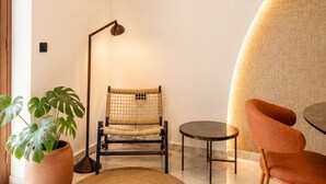 Un interior moderno con un tapete redondo, dos sillas, una lámpara de pie y una planta en maceta.