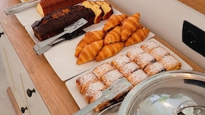 Un bufé con diferentes opciones de comida, incluyendo pasteles, frutas y una planta.
