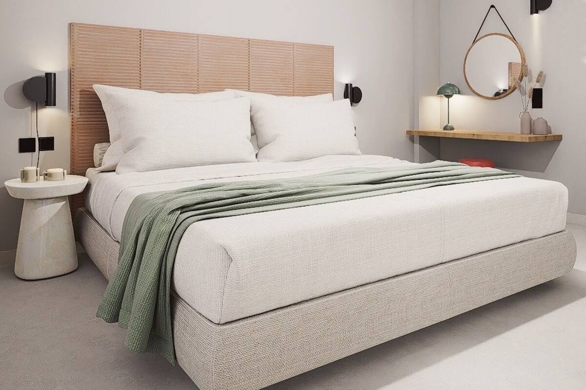 A modern bedroom with a bed, bedside tables, a nightstand, a wall-mounted lamp, and a mirror.
