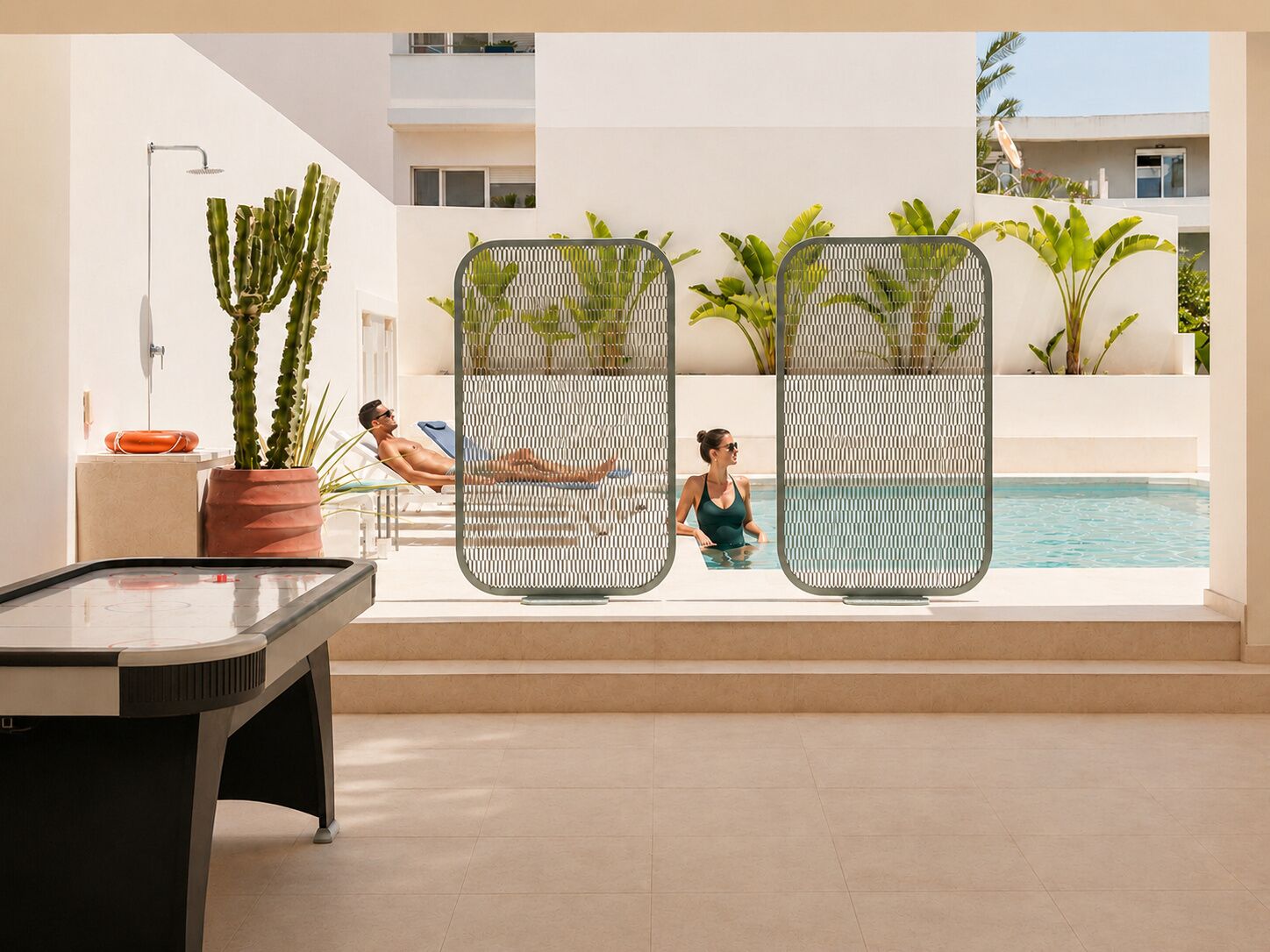 A pool area with a table, two potted plants, and a metal partition.