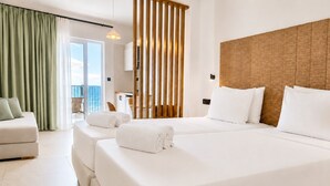 Habitación de hotel con una cama grande, un sofá, un balcón con vistas y un cabecero de madera.