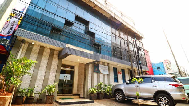 A modern building with a glass facade, a sign indicating a non-smoking policy, and several potted plants in front. - New Priok Indah Hotel (Jakarta)