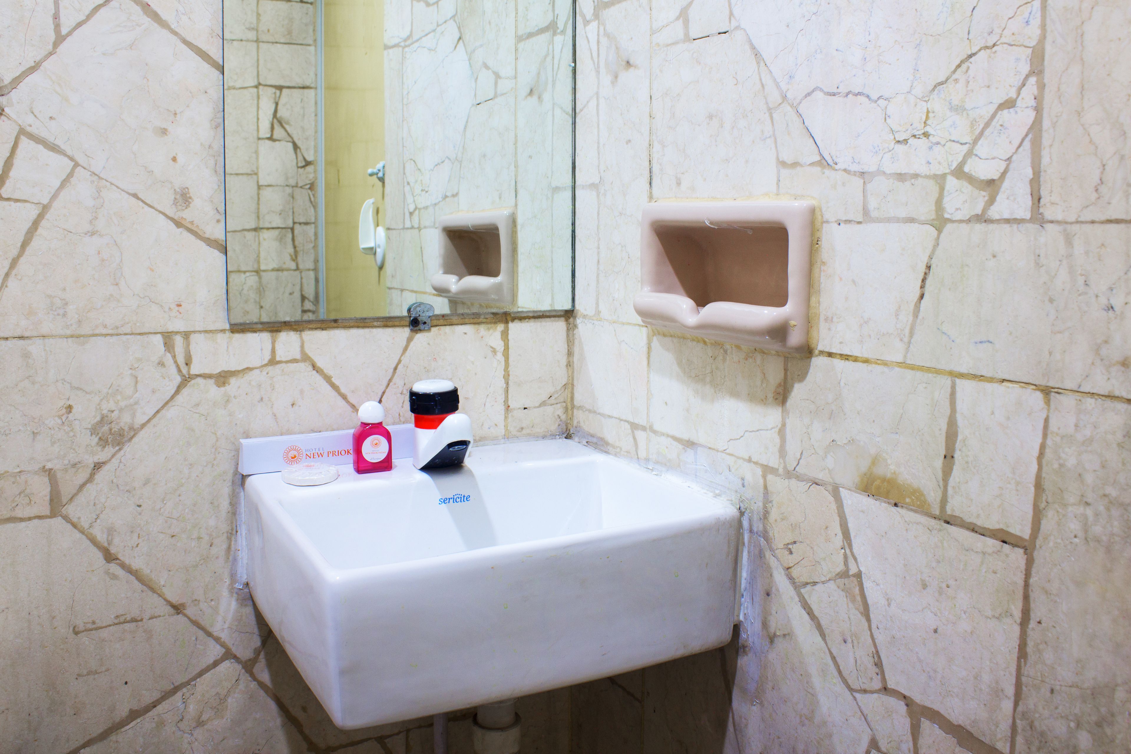 A bathroom with a white sink, a mirror, and a soap dispenser.