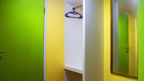 A room with a green door, a white wall, and a mirror reflecting a bathroom. - New Priok Indah Hotel (Jakarta)