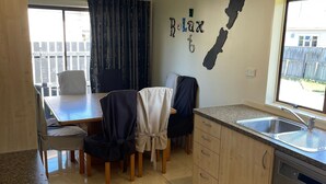 A modern kitchen with a dining area, a large window, and a 'Relax' wall decal. - Relax in Venice St with four bedrooms and two bathrooms minutes from the square (Martinborough)