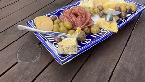 A wooden table with a plate of cheese, olives, crackers, and a bottle of wine. - Relax in Venice St with four bedrooms and two bathrooms minutes from the square (Martinborough)