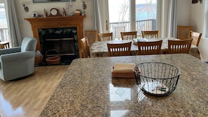 Un coin repas comprenant un îlot en granit, des chaises en bois, une cheminée et un tableau accroché au-dessus du manteau de la cheminée.