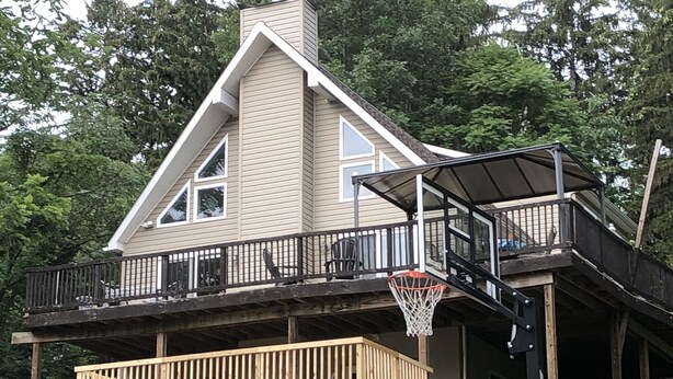 Une maison avec un panier de basketball installé sur une terrasse extérieure.