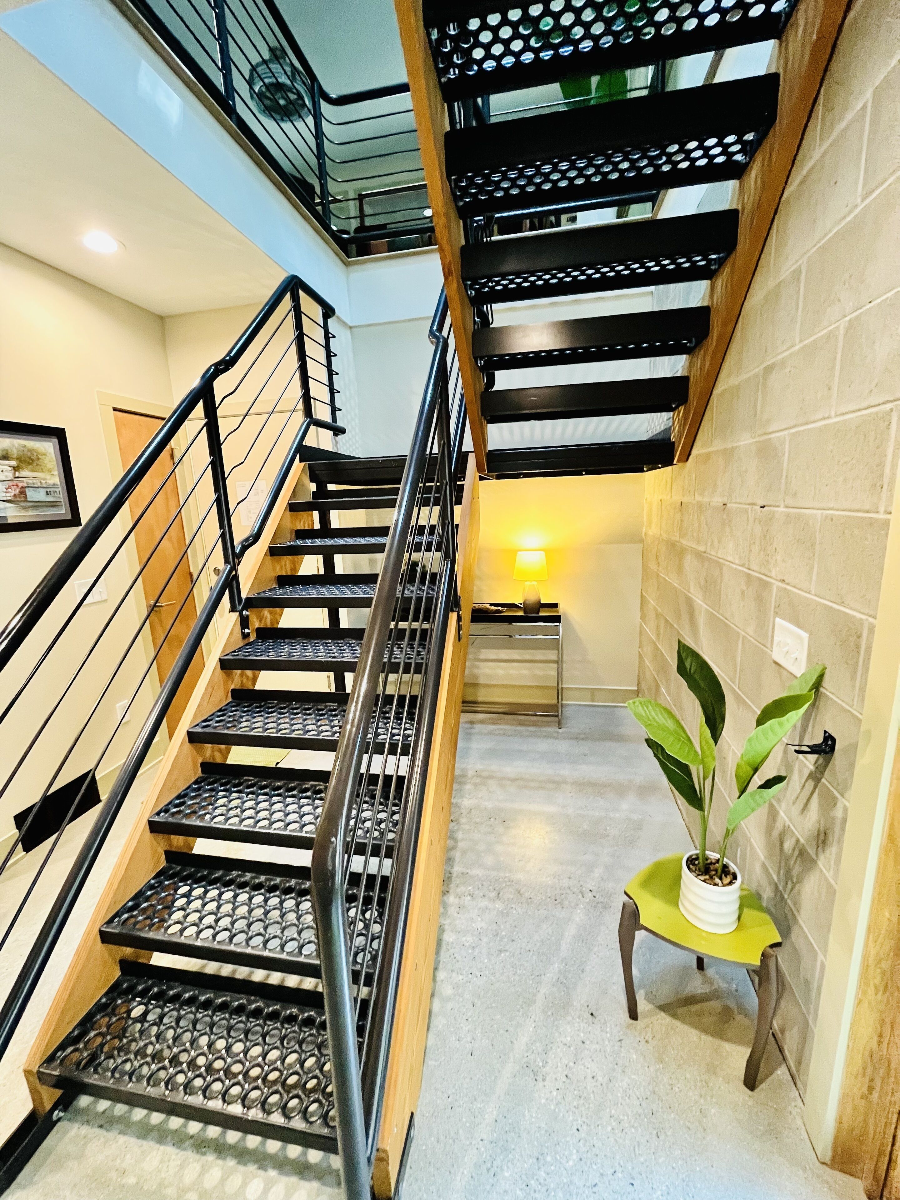 Una escalera con barandillas de metal y escalones de madera, que sube a un nivel superior.