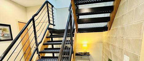 Una escalera con barandillas de metal y escalones de madera, que sube a un nivel superior.