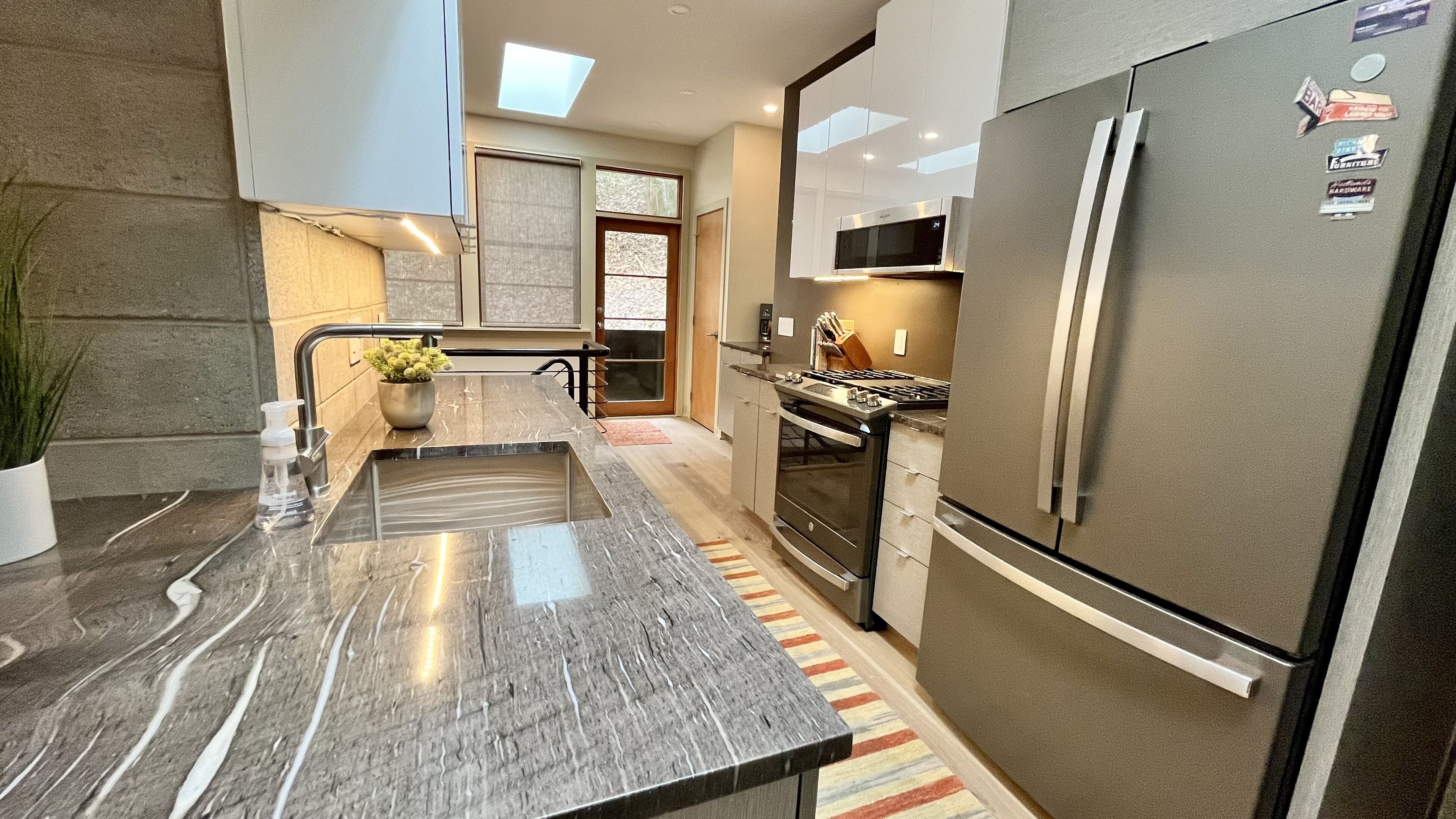 A modern kitchen with a stainless steel refrigerator, a built-in oven, and a microwave.