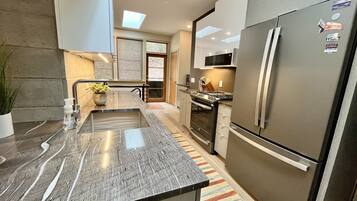 A modern kitchen with a stainless steel refrigerator, a built-in oven, and a microwave.