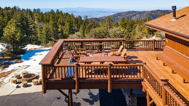 Une terrasse en bois avec des sièges extérieurs et une vue sur un paysage montagneux.