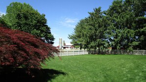 Un parque con césped, árboles y una valla blanca.
