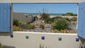 A view through a window with a beach and garden.
