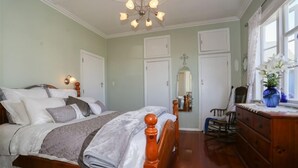 A bedroom with a wooden bed, a dresser, a chair, and a mirror. - Your personal ocean-front oasis (Haumoana)