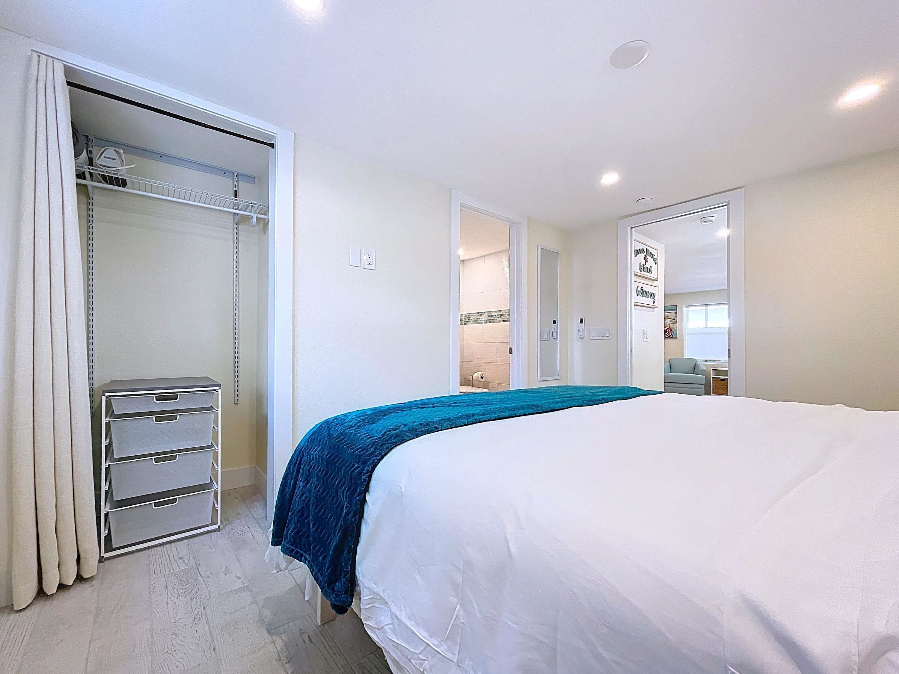 Een slaapkamer met een bed, een kledingkast en een badkamer zichtbaar door een geopende deur.