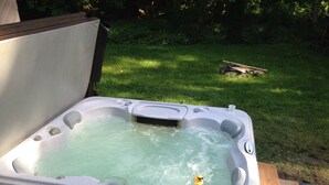 A hot tub with a wooden deck and a grassy yard in the background. - 2-Story Chalet, clean, 3Br / 2Ba in Snowline, best rates, WiFi and Hot Tub (Glacier)