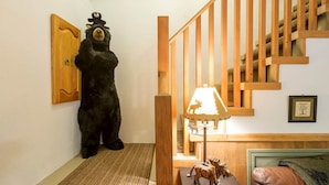 A room with a wooden staircase, a bear statue, a lamp with a moose design, and a framed picture on the wall. - 2-Story Chalet, clean, 3Br / 2Ba in Snowline, best rates, WiFi and Hot Tub (Glacier)