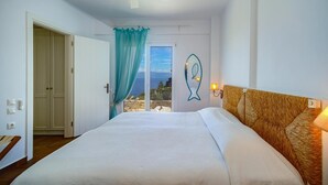 A bedroom with a bed, a ceiling fan, a view through a door, and a wall-mounted light fixture.