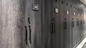 Una fila de taquillas de madera oscura con placas numeradas, cada una con un asa y una pequeña rejilla.