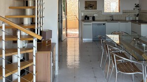 Une cuisine moderne avec un coin repas, un escalier et un mur en pierre.