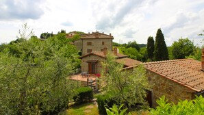 A stone building with a tiled roof, surrounded by lush greenery and trees.