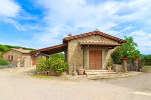 A stone building with a tiled roof, a wooden door, and potted plants. - Stunning private villa for 20 guests with private pool, WIFI, TV, terrace and pets allowed (Arezzo)