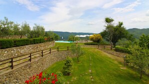 A landscaped garden with a stone wall, a grassy lawn, and a view of a mountain range.