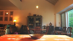 Ein Esszimmer mit einem Tisch für vier Personen, einer Vitrine mit Glastüren und einem Fenster mit Jalousien.