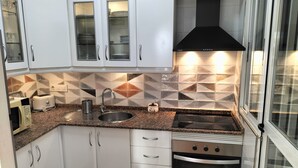 A modern kitchen with white cabinets, a granite countertop, a stainless steel sink, a toaster, a kettle, and a black range hood. - House with terrace of flowers and solarium, near beaches, A/C, wifi, Sat TV, BBQ (San Juan de los Terreros)