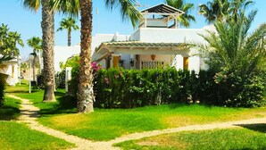 A well-maintained garden with a clear path leading to a white building with a tiled roof and a balcony. - House with terrace of flowers and solarium, near beaches, A/C, wifi, Sat TV, BBQ (San Juan de los Terreros)