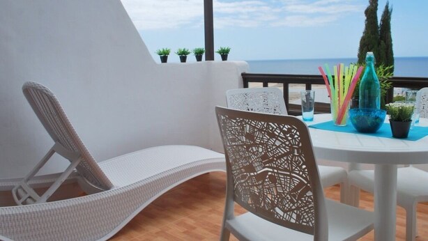 A balcony with a white chair and table, potted plants, and a view of the sea. - Quiet apartment near the beach VV-35-3-0002306 (Tías)