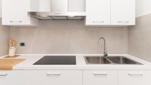 A modern kitchen with white cabinets, a stainless steel sink, and a black countertop. - Fantastic holiday apartment with sea view - Villa Nina (San Teodoro)