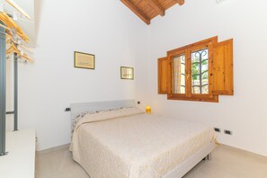 Un dormitorio con cama, persianas de madera y una lámpara fijada a la pared.