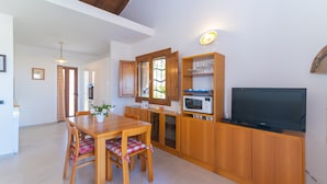 A modern kitchen with wooden cabinets, a dining table with chairs, a microwave, and a television. - Fantastic holiday apartment with sea view - Villa Nina (San Teodoro)