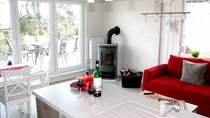 A modern kitchen with a built-in stove, white cabinetry, and a dining area with white chairs.