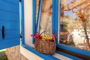 A wicker basket with red berries and yellow flowers on a windowsill.