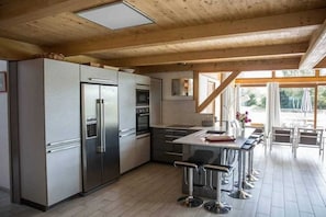 Eine moderne Küche mit Edelstahlgeräten, einer Bar und großen Fenstern.