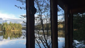 Eine Hütte mit Blick auf einen stillen See, umgeben von Bäumen.