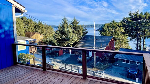 Une terrasse en bois offrant une vue sur un quartier résidentiel, un plan d’eau et des arbres.