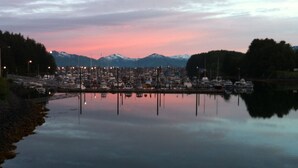 Un port de plaisance avec des bateaux amarrés, une eau calme et des montagnes en arrière-plan.